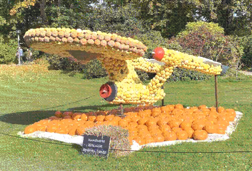 A dithered photo of a large model the original Enterprise made out of squash and wood accents.